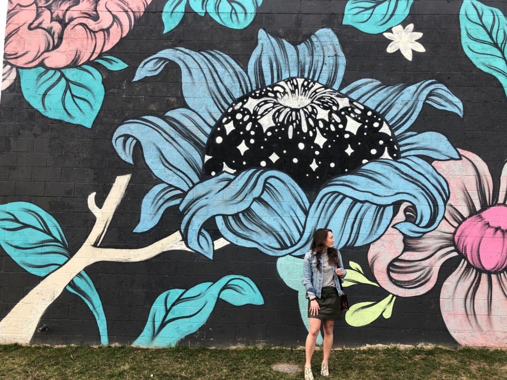 Denim jacket with green faux leather skirt at floral mural