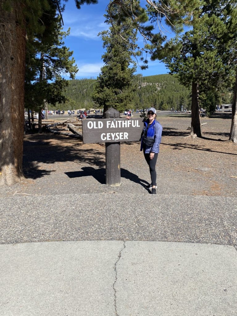 Madeline Mihaly with the Old Faithful Sign in Yellowstone